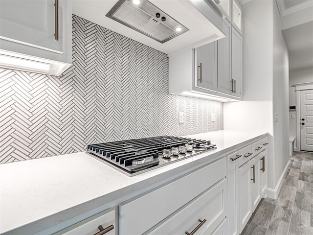 kitchen with premium range hood, white cabinetry, tasteful backsplash, stainless steel gas stovetop, and light wood-type flooring