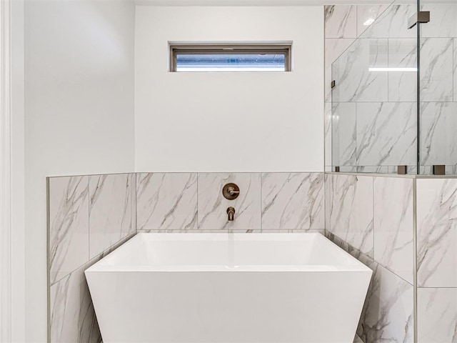 bathroom featuring a bath and tile walls