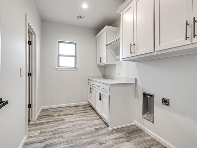 laundry area with cabinets, hookup for an electric dryer, and light hardwood / wood-style floors