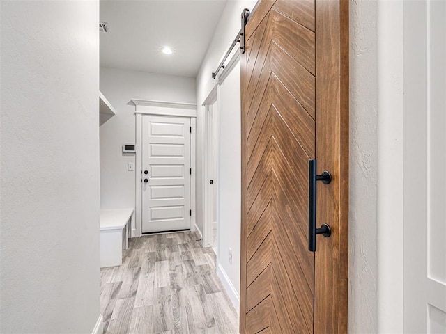 corridor featuring a barn door and light wood-type flooring