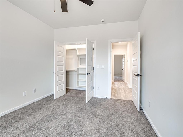 unfurnished bedroom featuring a spacious closet, ceiling fan, and carpet