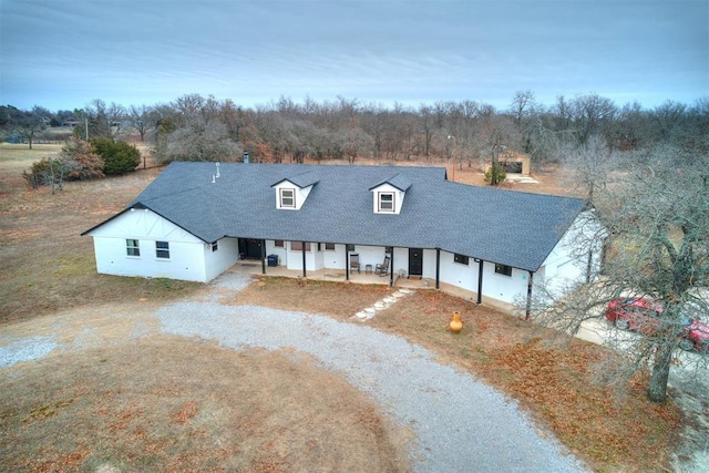 view of front of home featuring roof with shingles and dirt driveway