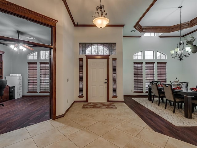 tiled entrance foyer with a towering ceiling, ornamental molding, and plenty of natural light