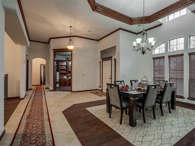 tiled dining space featuring a notable chandelier, crown molding, and a high ceiling