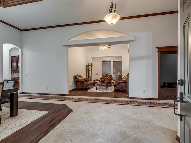 tiled entryway featuring ceiling fan and ornamental molding