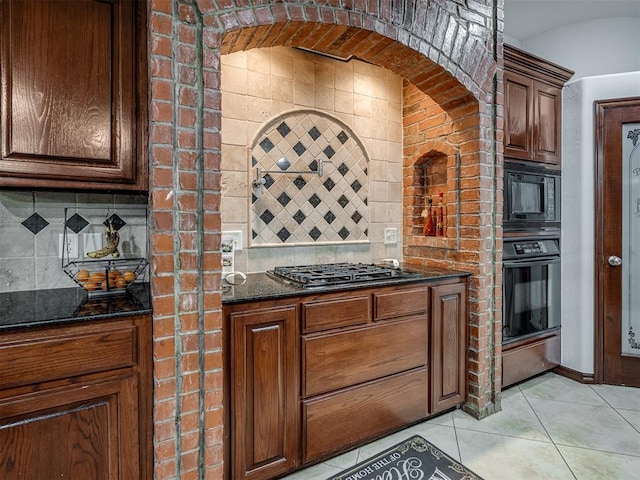 kitchen with dark stone countertops, decorative backsplash, light tile patterned floors, and black appliances