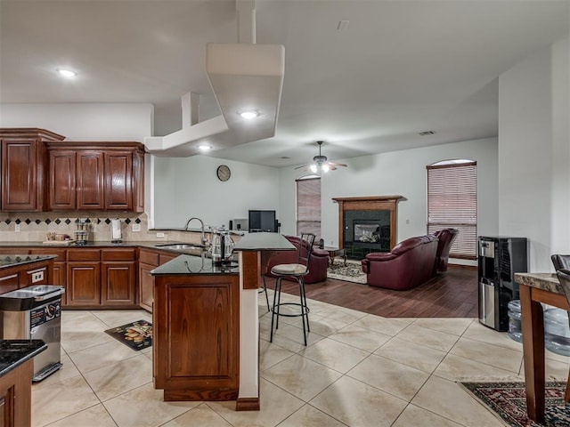 kitchen with a breakfast bar, tasteful backsplash, sink, light tile patterned floors, and ceiling fan