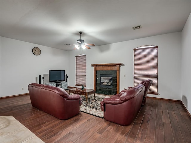 living room with dark wood-type flooring, ceiling fan, and a tile fireplace