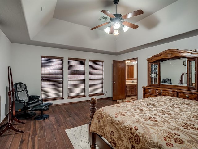 bedroom with sink, ceiling fan, dark hardwood / wood-style floors, connected bathroom, and a tray ceiling