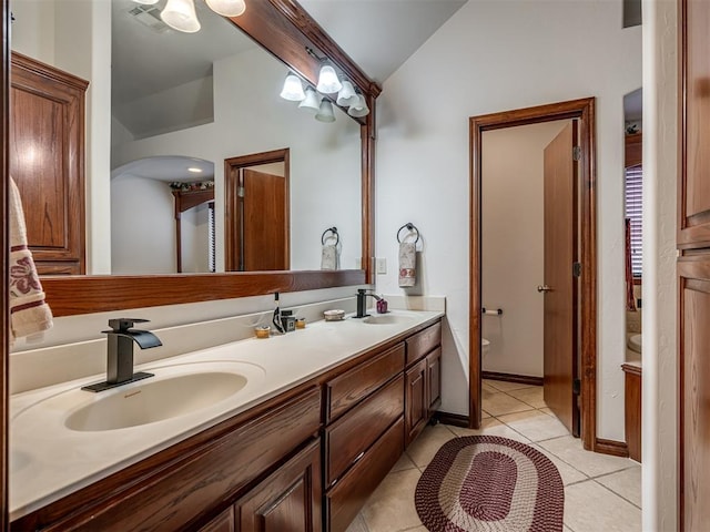 bathroom with lofted ceiling, vanity, tile patterned flooring, and toilet