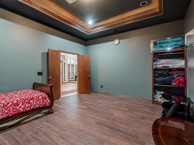 bedroom with wood-type flooring and a tray ceiling