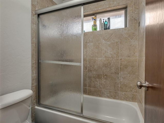 bathroom with shower / bath combination with glass door and toilet