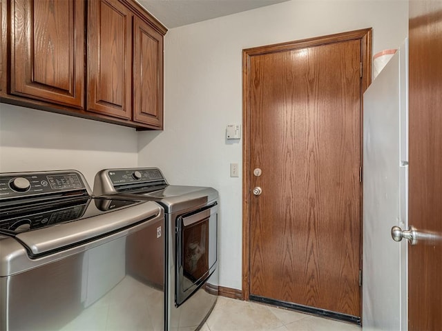 clothes washing area featuring cabinets, washing machine and clothes dryer, and light tile patterned flooring