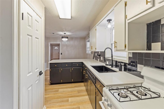 kitchen featuring white cabinetry, sink, decorative backsplash, light hardwood / wood-style floors, and gas range gas stove