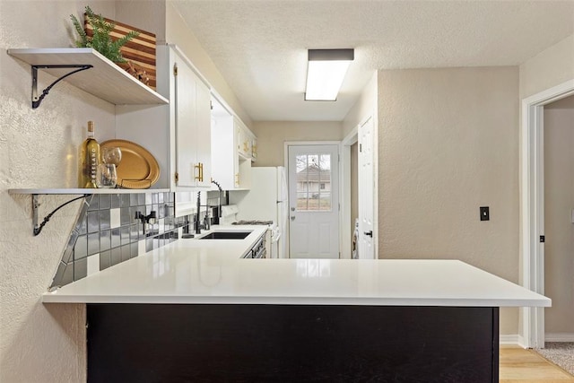 kitchen featuring white cabinetry, kitchen peninsula, and a textured ceiling