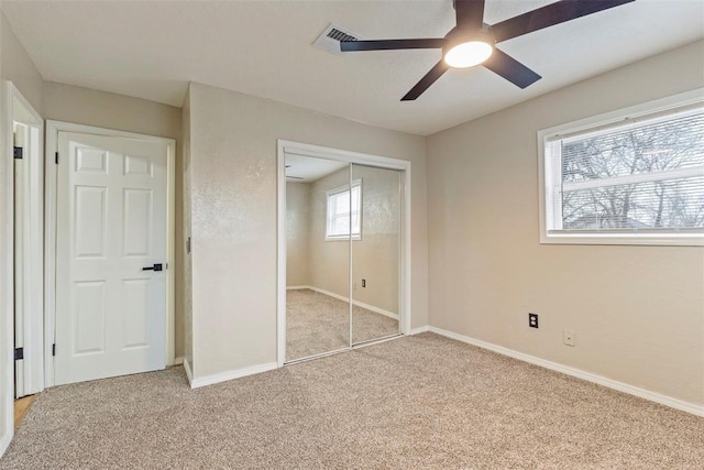 unfurnished bedroom with light carpet, a closet, and ceiling fan