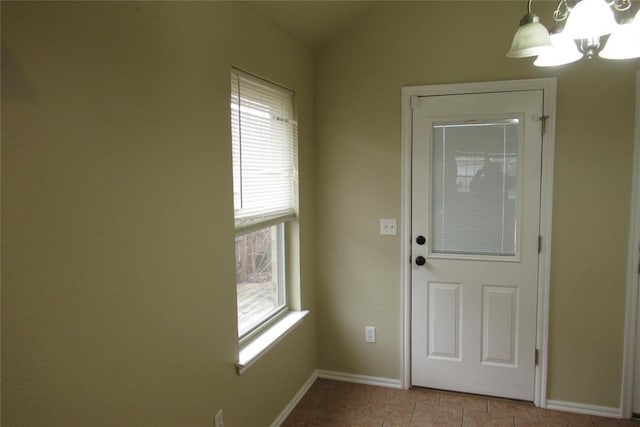 doorway to outside featuring light tile patterned floors, baseboards, a chandelier, and vaulted ceiling