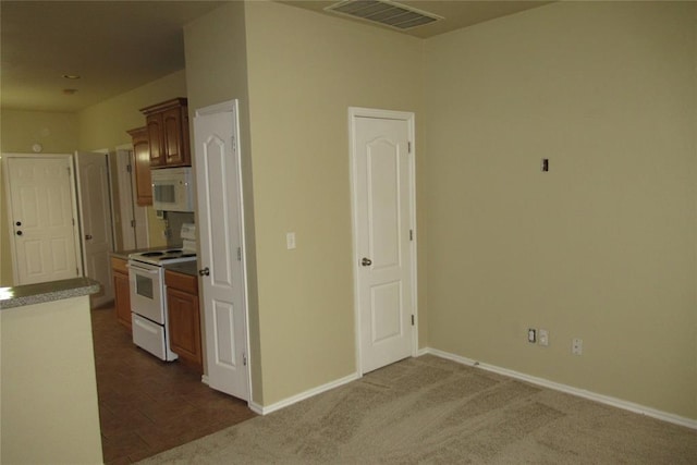 kitchen with dark colored carpet, visible vents, white appliances, and baseboards