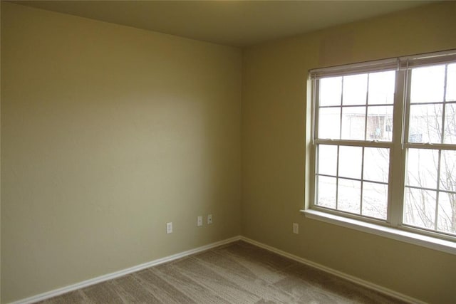 empty room featuring carpet flooring, a healthy amount of sunlight, and baseboards