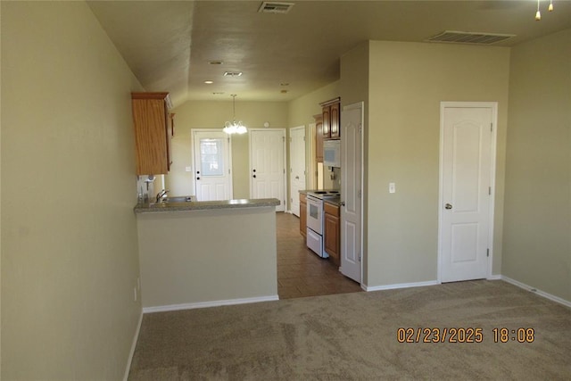 kitchen with hanging light fixtures, white appliances, visible vents, and dark carpet