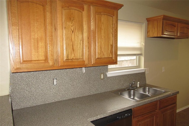 kitchen with dishwashing machine, backsplash, brown cabinets, and a sink