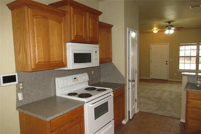 kitchen featuring white appliances, brown cabinetry, carpet, and visible vents