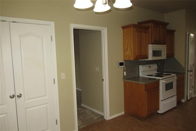 kitchen featuring baseboards, a chandelier, decorative backsplash, brown cabinets, and white appliances