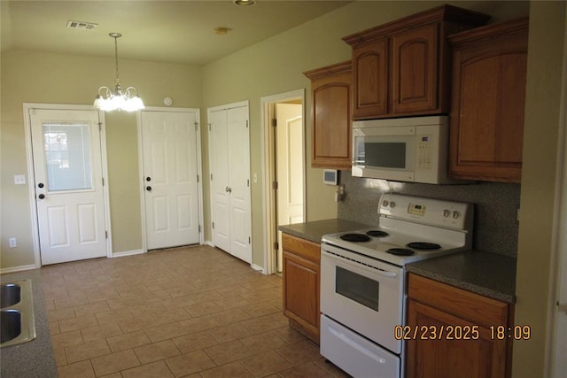 kitchen with visible vents, pendant lighting, dark countertops, white appliances, and an inviting chandelier