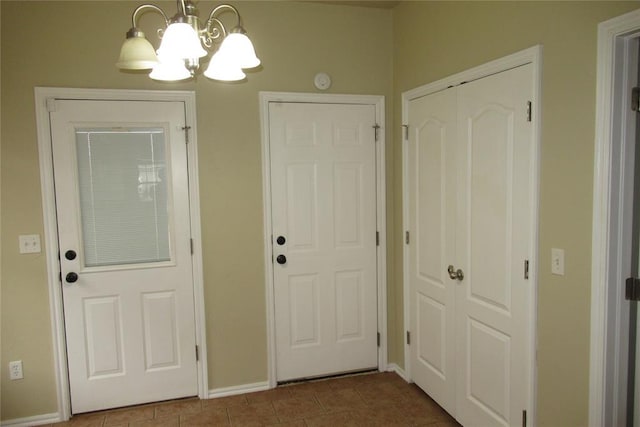 doorway to outside featuring tile patterned flooring, a notable chandelier, and baseboards