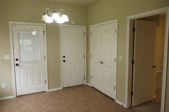 foyer entrance with light tile patterned floors, baseboards, and a chandelier