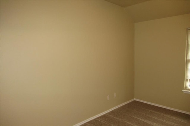 unfurnished room with baseboards and dark carpet