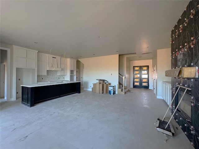 kitchen with tasteful backsplash, wall chimney range hood, a kitchen island, and white cabinets