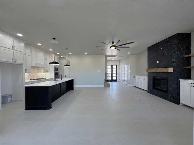 7225 NW 154th St, Edmond, OK 73013 - kitchen featuring a center island with sink, stainless steel gas cooktop, a fireplace, open floor plan, and ceiling fan