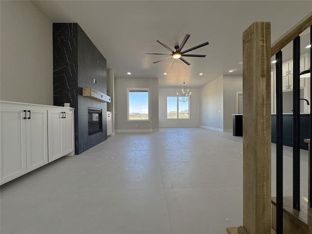 7225 NW 154th St, Edmond, OK 73013 - unfurnished living room with ceiling fan with notable chandelier, baseboards, a fireplace, and recessed lighting
