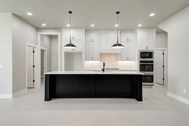 7225 NW 154th St, Edmond, OK 73013 - kitchen featuring stainless steel appliances, tasteful backsplash, white cabinets, light countertops, and a kitchen island with sink