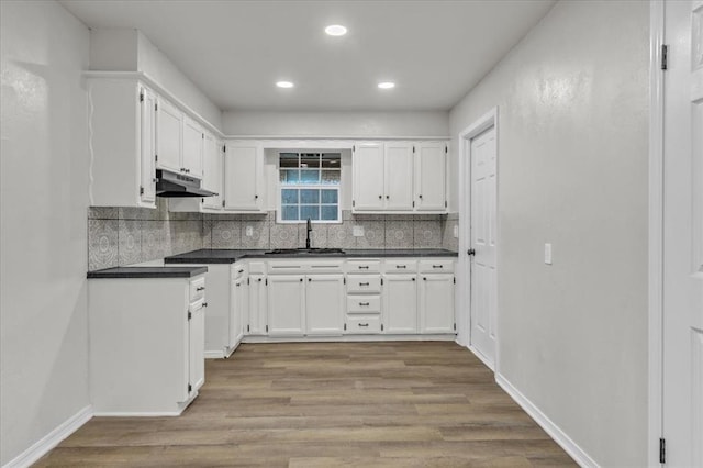 kitchen featuring white cabinetry, sink, backsplash, and light hardwood / wood-style flooring