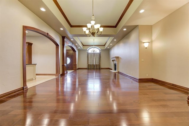 foyer featuring hardwood / wood-style flooring, crown molding, a raised ceiling, and a notable chandelier