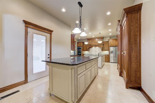 kitchen featuring stainless steel appliances, hanging light fixtures, a kitchen island, and dark stone counters