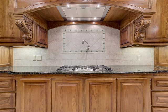 kitchen with dark stone countertops, decorative backsplash, and stainless steel gas cooktop