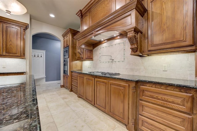 kitchen featuring tasteful backsplash, light tile patterned floors, dark stone counters, and appliances with stainless steel finishes