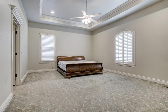 carpeted bedroom with ceiling fan, ornamental molding, and a raised ceiling