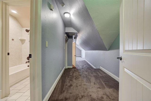 corridor featuring vaulted ceiling, light carpet, and a textured ceiling