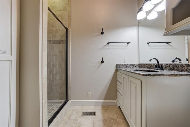 bathroom featuring a shower with door, vanity, and tile patterned flooring