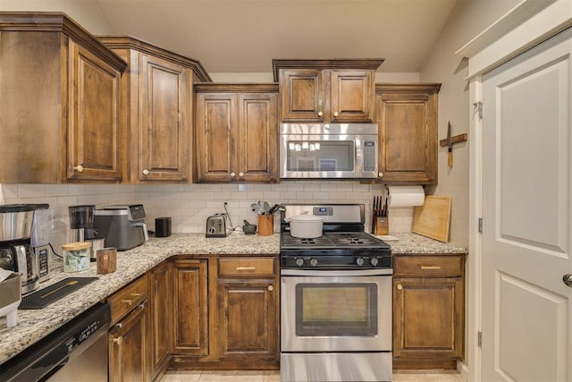 8609 SW 36th Ter, Oklahoma City, OK 73179 - kitchen featuring appliances with stainless steel finishes, decorative backsplash, light stone counters, and brown cabinets