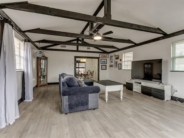 living room featuring a healthy amount of sunlight, light hardwood / wood-style floors, and lofted ceiling with beams