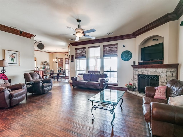 living room with ornamental molding, a stone fireplace, dark wood-type flooring, and ceiling fan