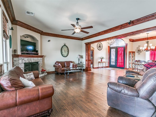 living room featuring crown molding, dark wood-type flooring, ceiling fan with notable chandelier, and a fireplace