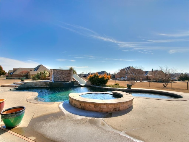 view of swimming pool featuring an in ground hot tub, a water slide, and a patio area