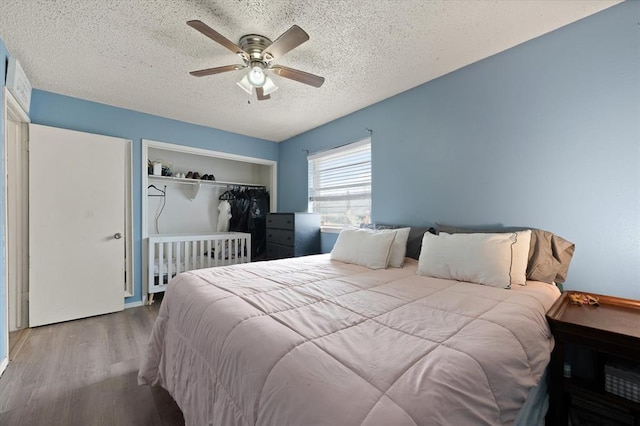 bedroom with hardwood / wood-style flooring, ceiling fan, and a textured ceiling