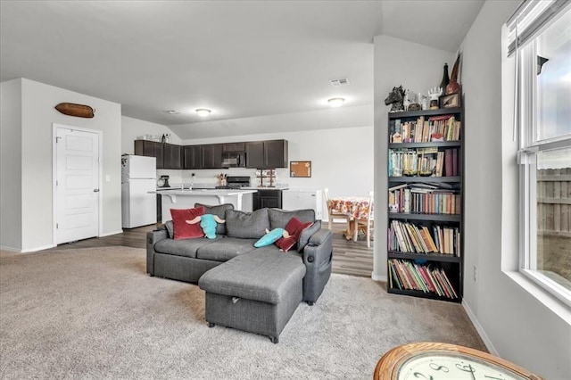 carpeted living room with a wealth of natural light and vaulted ceiling